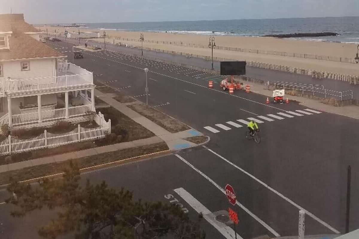 A coastal road with a stop sign, beach, and a building with a balcony.