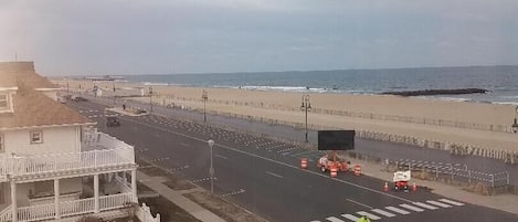 A coastal road with a stop sign, beach, and a building with a balcony.