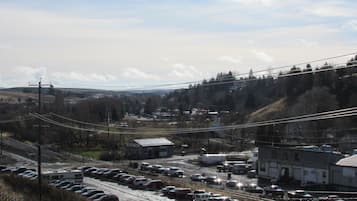 A parking lot with multiple vehicles, a building with a sign, and a hilly landscape in the background.