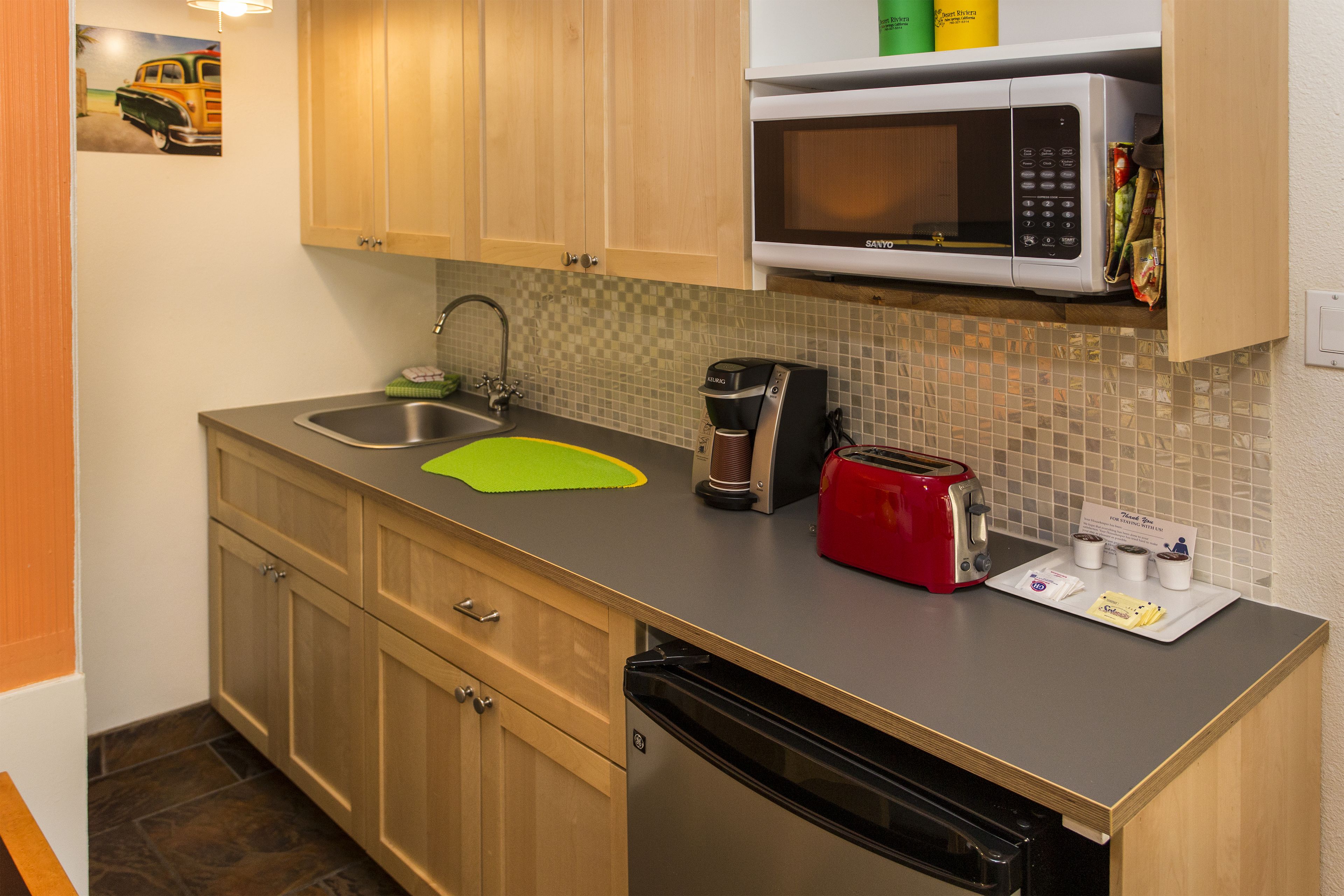 A compact kitchen with wooden cabinets, a microwave, a toaster, and a coffee maker.