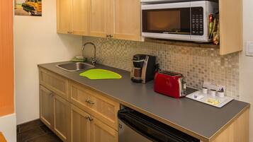 A compact kitchen with wooden cabinets, a microwave, a toaster, and a coffee maker.