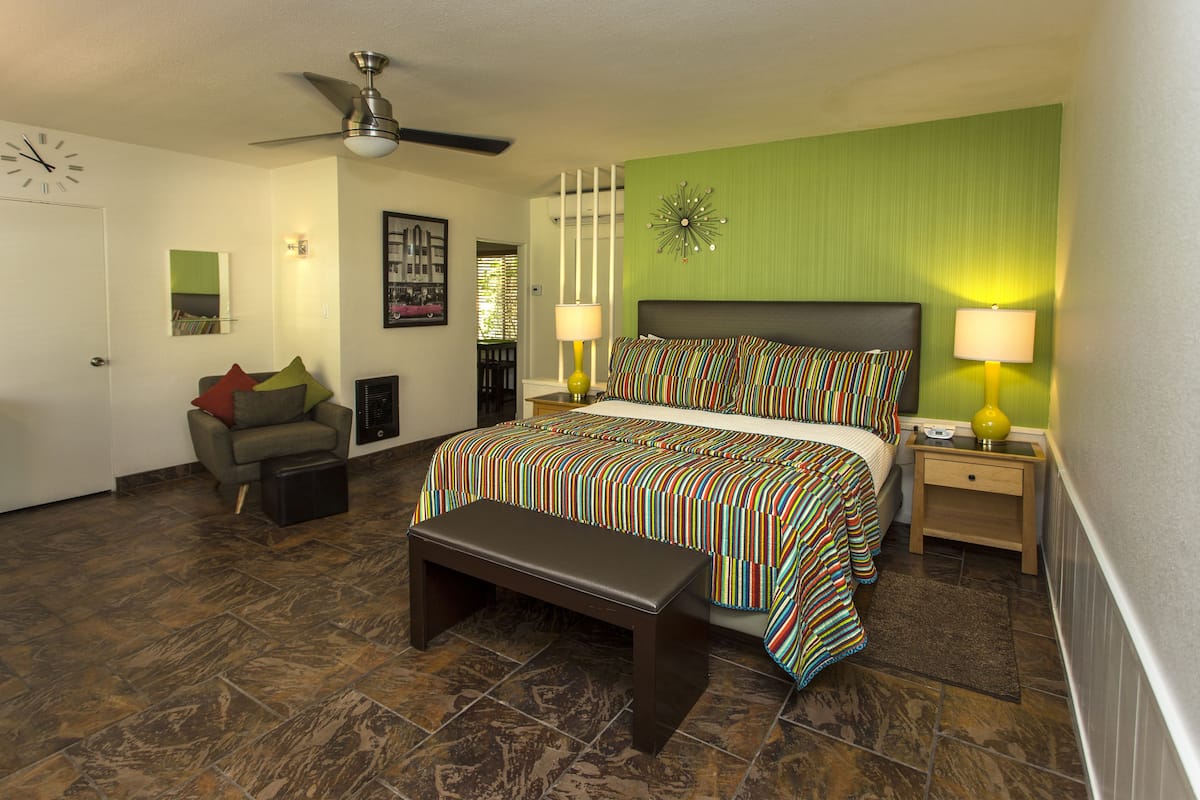A bedroom with a bed, bench, nightstands, and a ceiling fan.