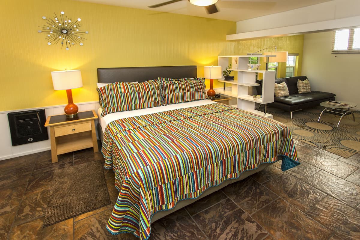 A hotel room with a large bed, two bedside tables, a sofa, and a small coffee table.