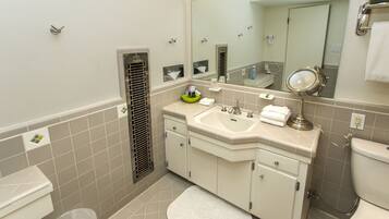 A bathroom with a toilet, sink, mirror, and a towel rack.