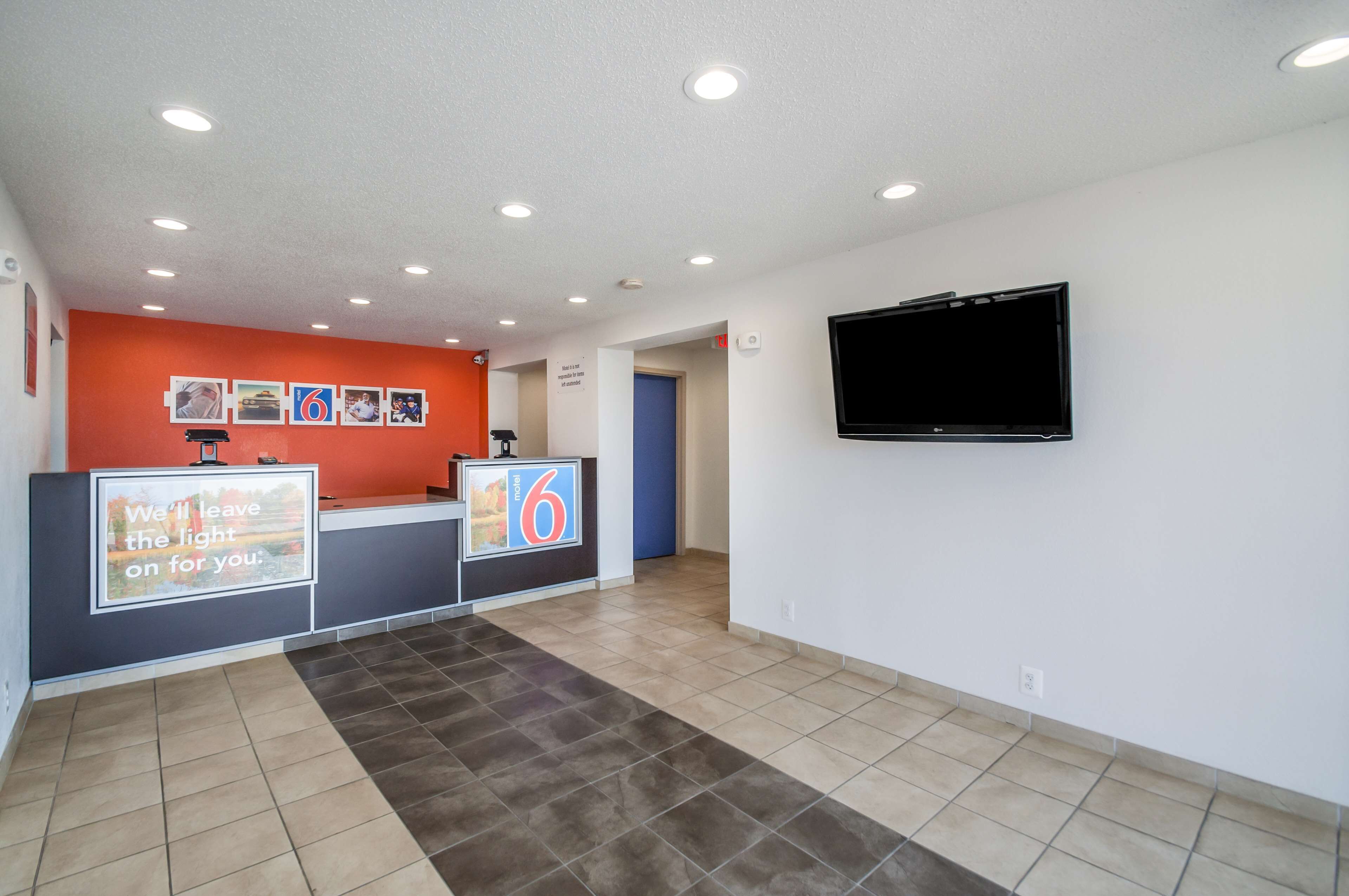 A reception area with a counter, a television mounted on the wall, and a sign with the number 6.