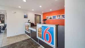 Ein Hotel-Rezeptionsbereich mit modernem Design, inklusive einer Rezeption, einem Telefon und einer digitalen Anzeige.