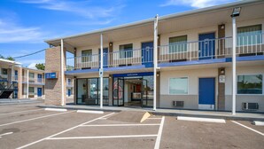Ein Motel mit zweistöckigem Bau, überdachter Rezeption und Parkplatz.