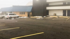 A parking lot with several cars, a building with a blue roof, and a large black structure.