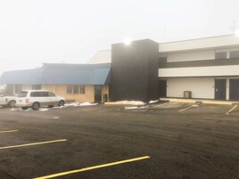 A parking lot with several cars, a building with a blue roof, and a large black structure.