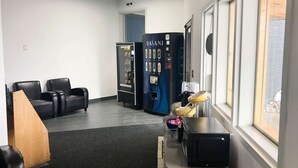 A room with black leather chairs, a vending machine, a microwave, and a window with a view of the outside.