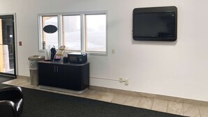 A room with a black entertainment unit, a ceiling fan, a large window, and a wall-mounted TV.