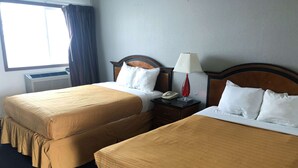 A hotel room with two beds, a nightstand, a lamp, and a telephone.