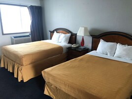 A hotel room with two beds, a nightstand, a lamp, and a telephone.