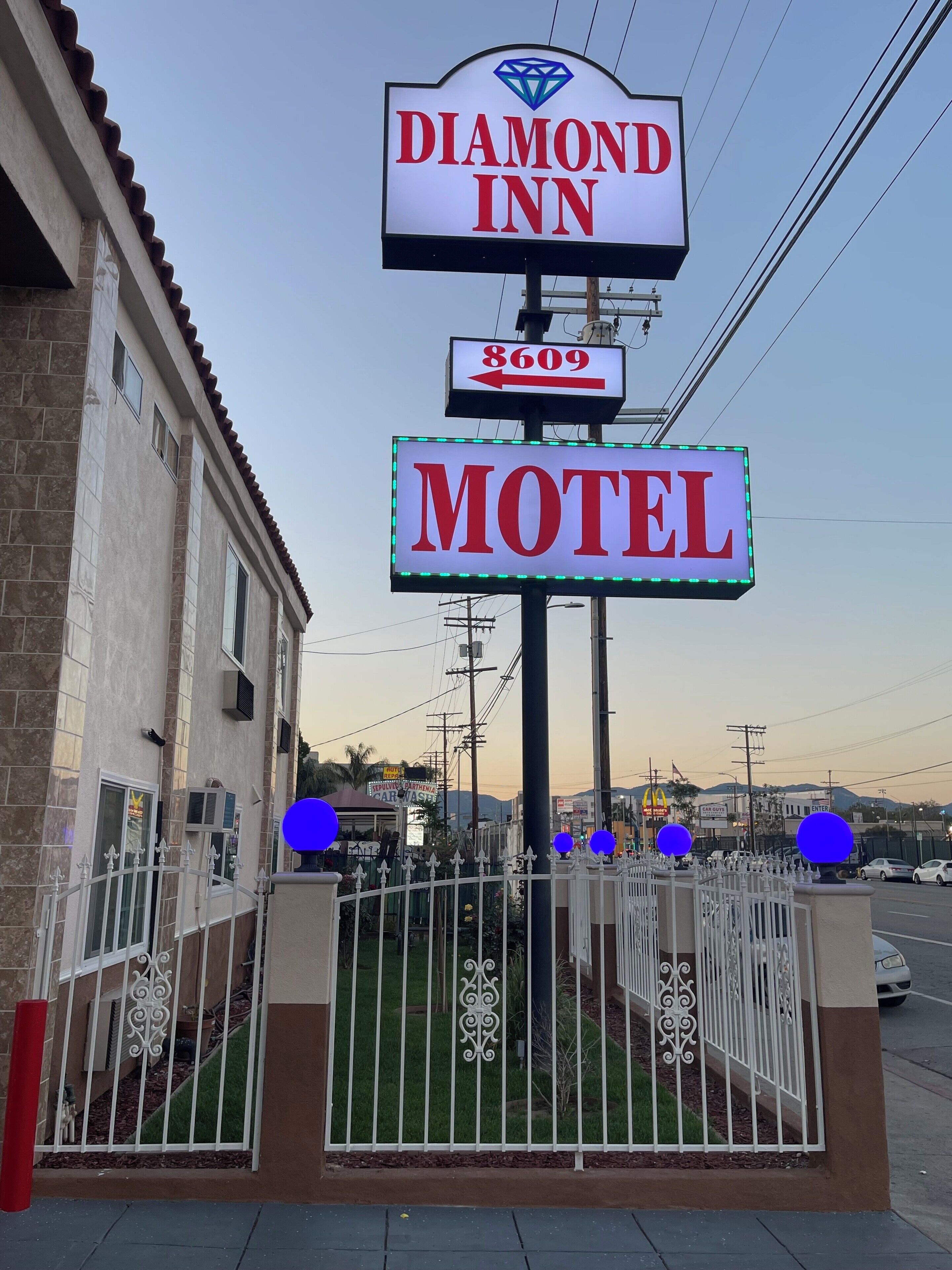 Une enseigne du motel Diamond Inn, avec un numéro de téléphone, une entrée fermée par un portail et un ciel dégagé en arrière-plan.