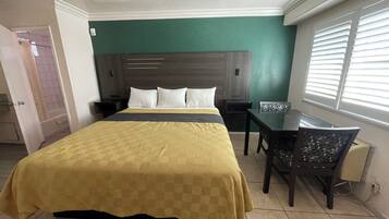 A hotel room with a large bed, a desk, and a chair.