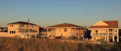 A beachfront hotel with multiple buildings, including a main structure with a balcony and a smaller annex.