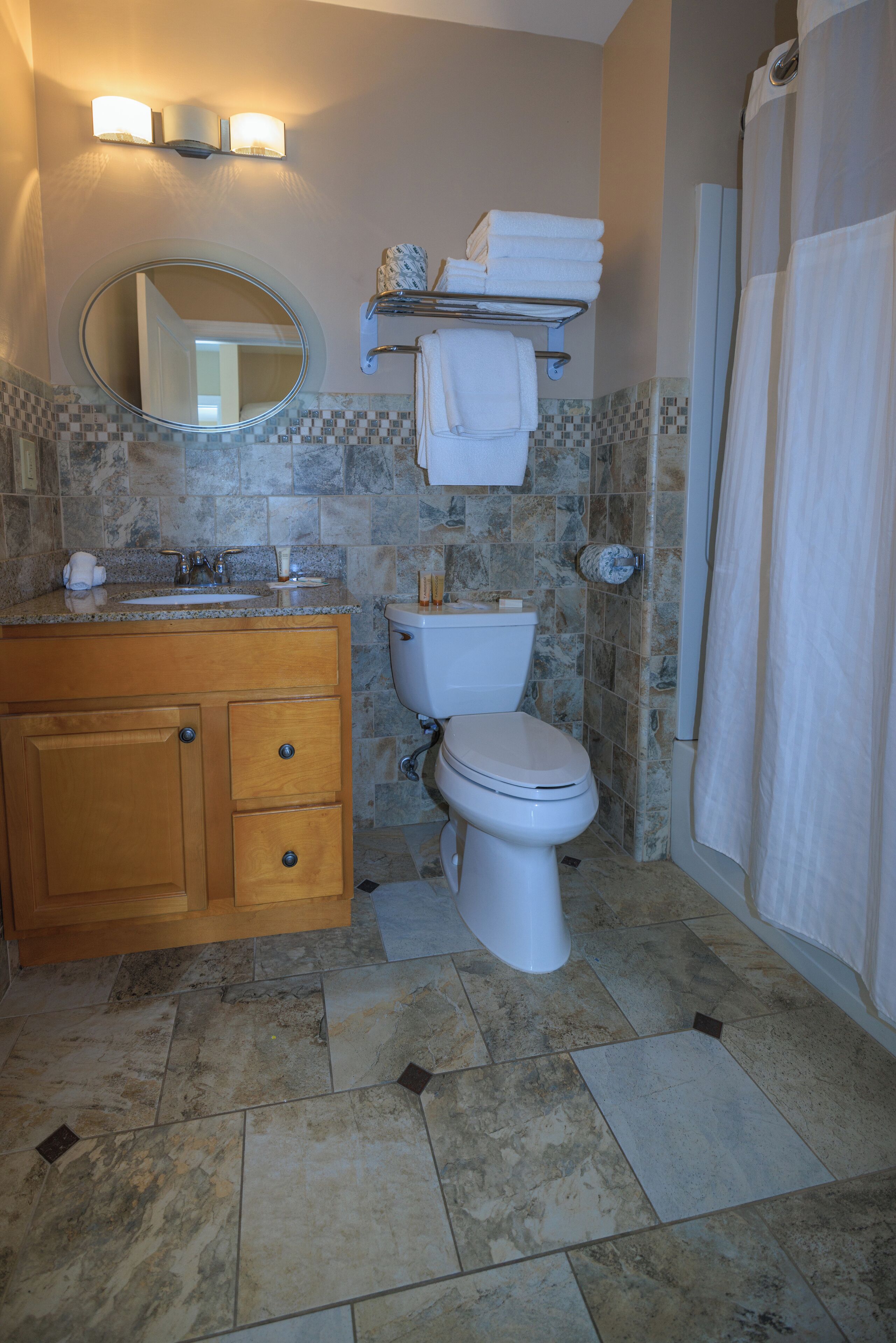 A bathroom with a toilet, sink, mirror, and shower curtain.
