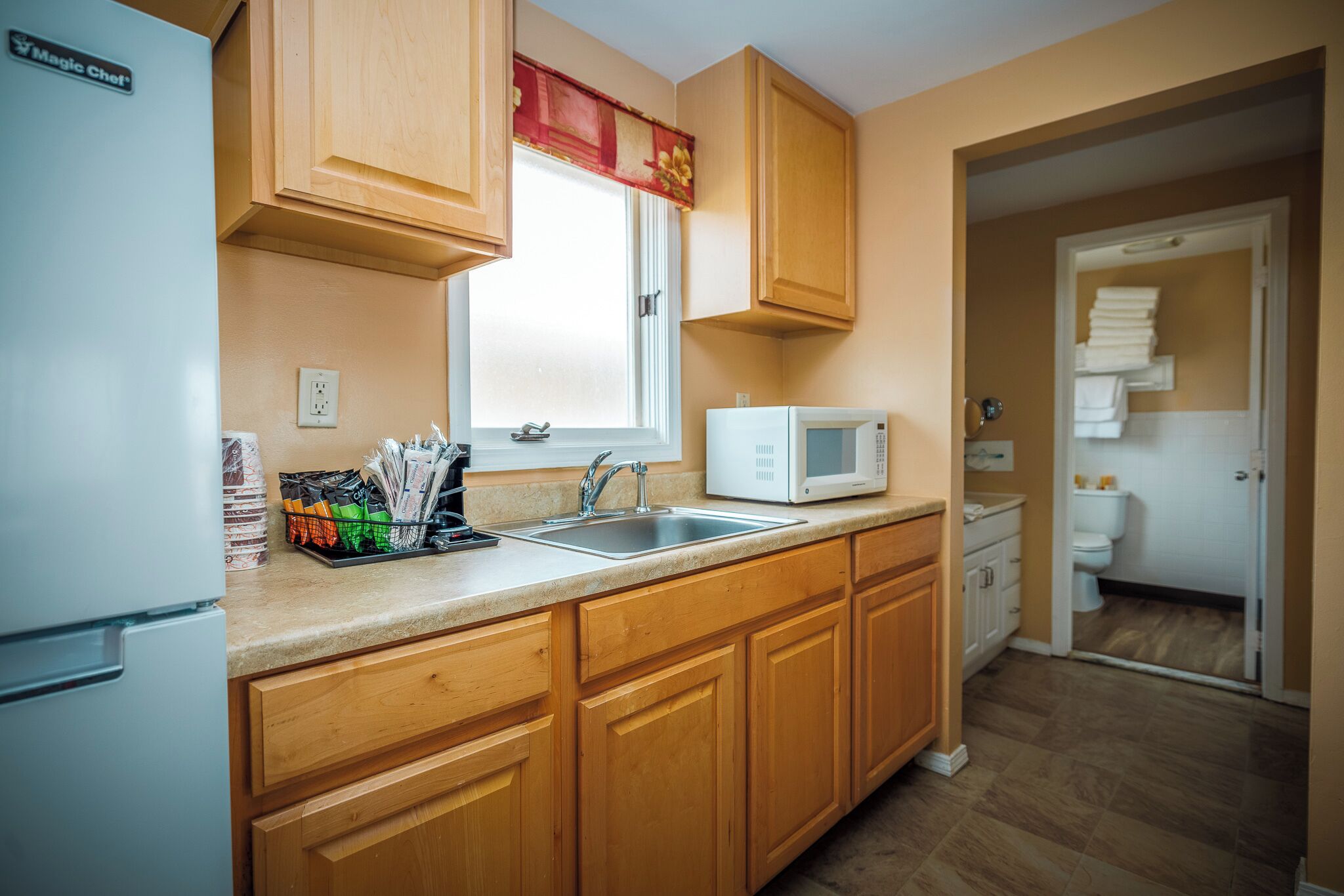 A kitchen with wooden cabinets, a white refrigerator, a microwave, and a sink.