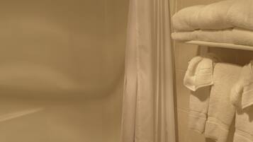 A bathroom with a bathtub, toilet, and a towel rack with folded towels.
