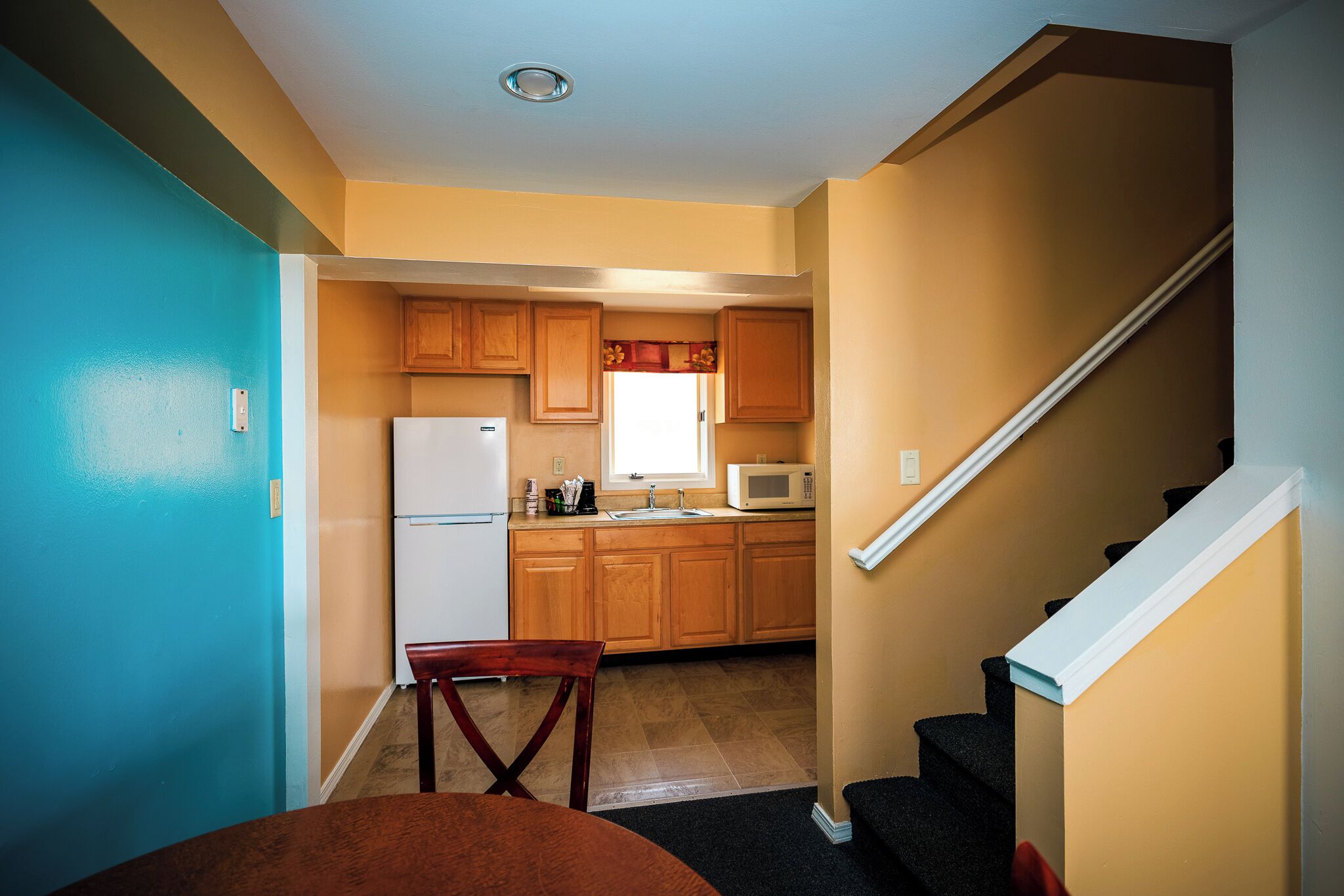A compact kitchen with wooden cabinets, a white refrigerator, and a microwave.