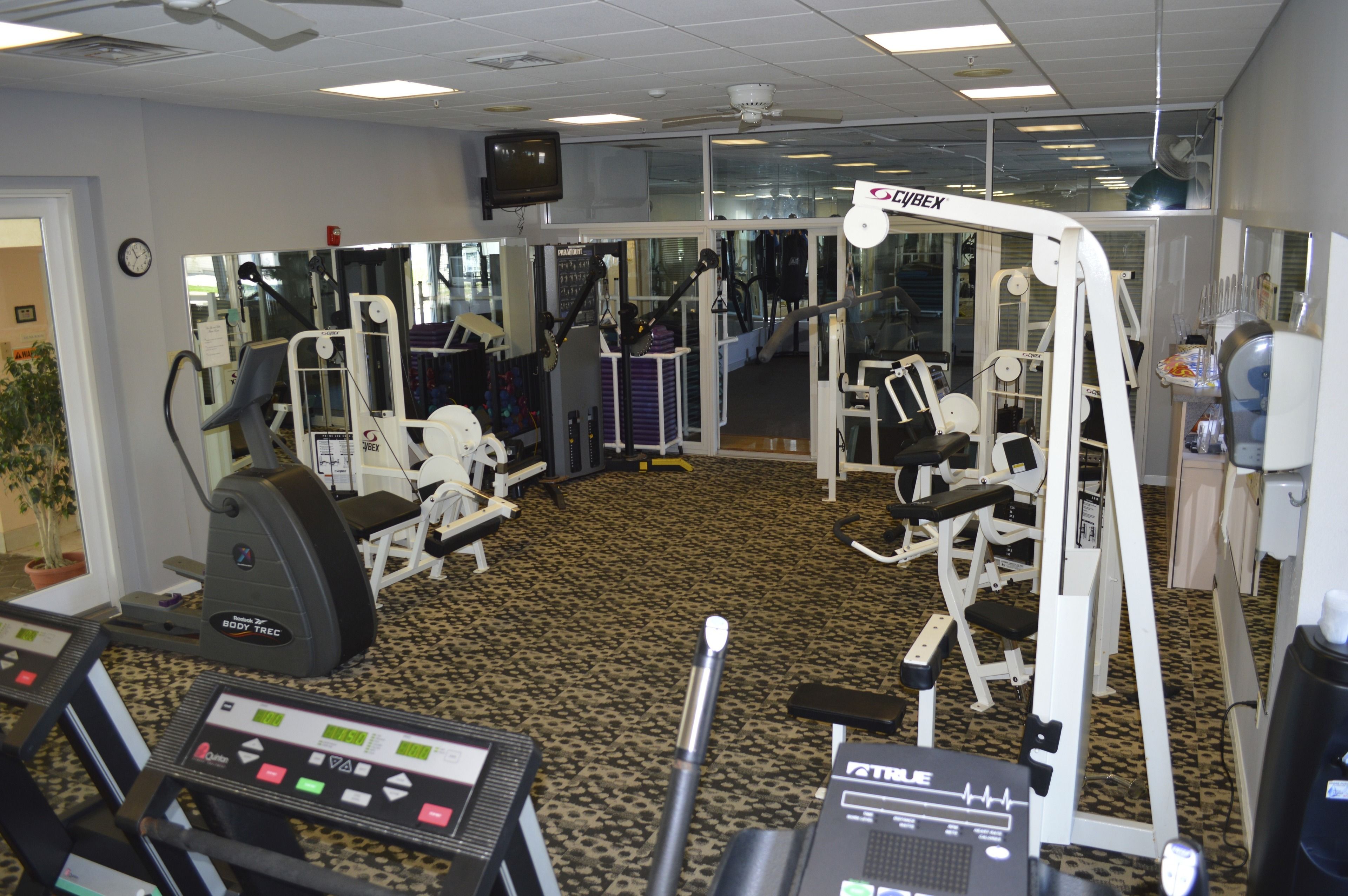 A gym with cardio machines, weight stations, and mirrors.