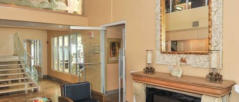 A spacious lobby with wicker furniture, a grand chandelier, and a large ornate mirror.