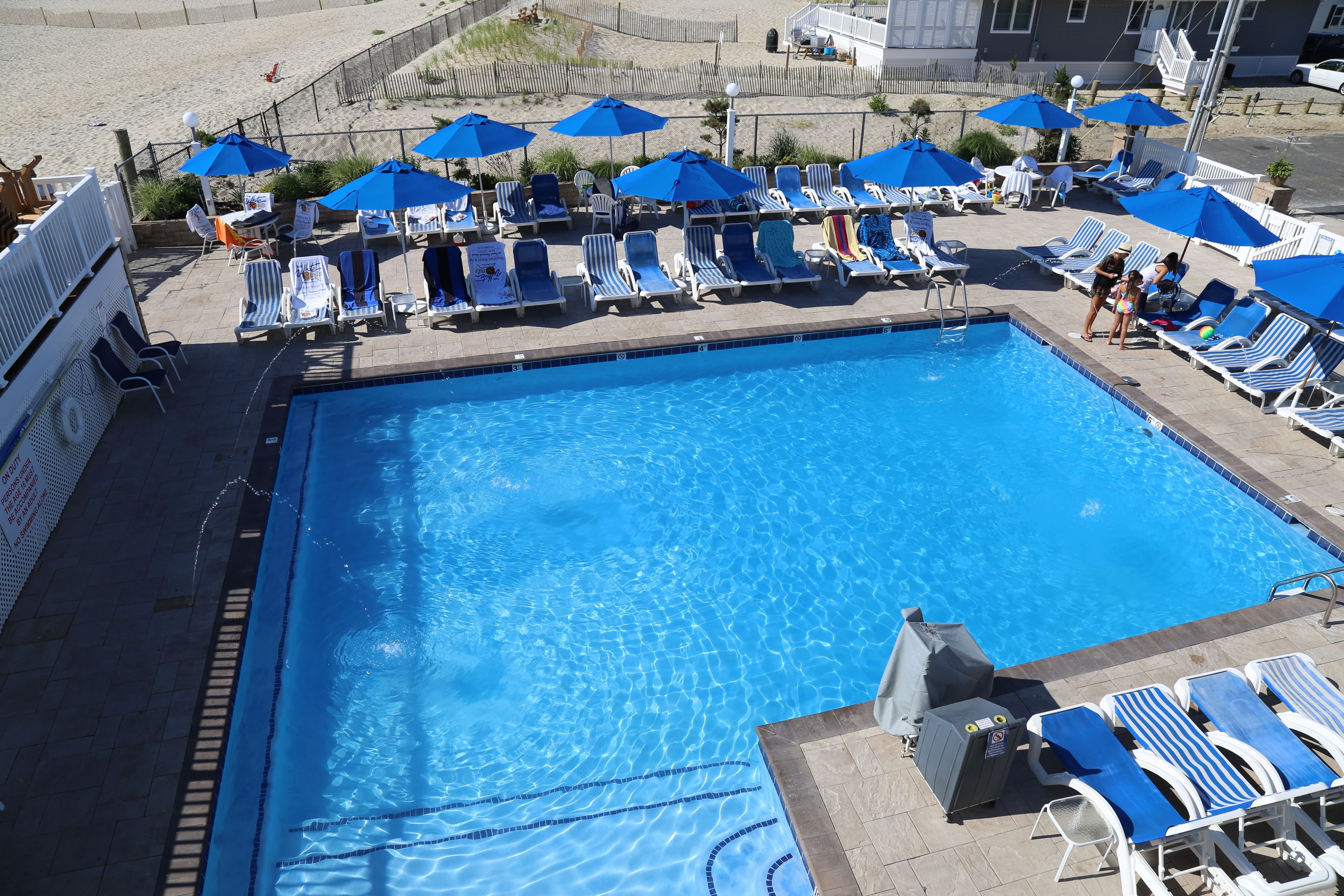 A swimming pool with blue umbrellas and lounge chairs.