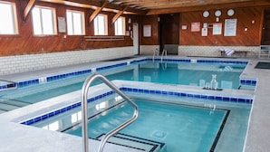 An indoor swimming pool with clear water, wooden walls, and multiple signs including pool rules. - Blue Heron Motel (Nags Head)