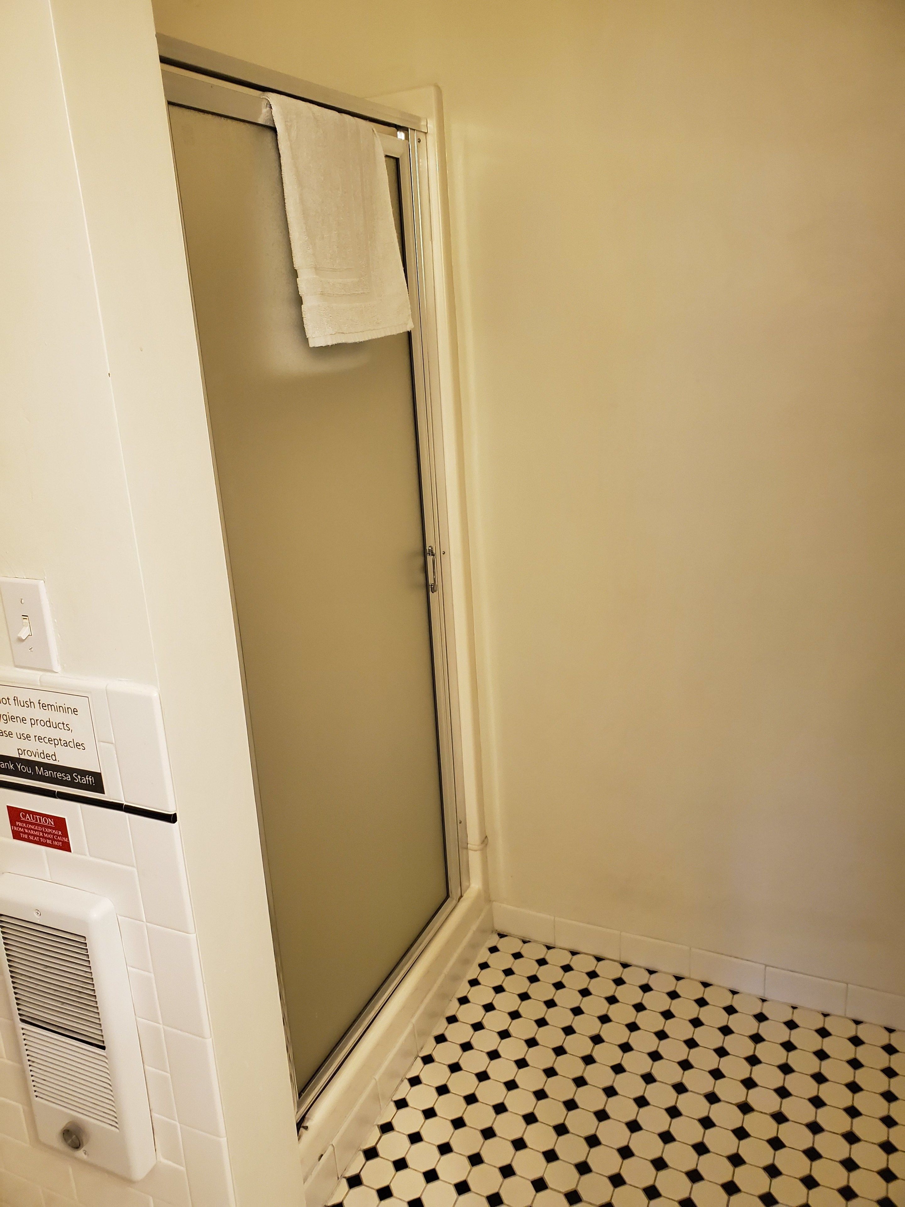 A bathroom with a shower, a toilet, and a hand dryer.