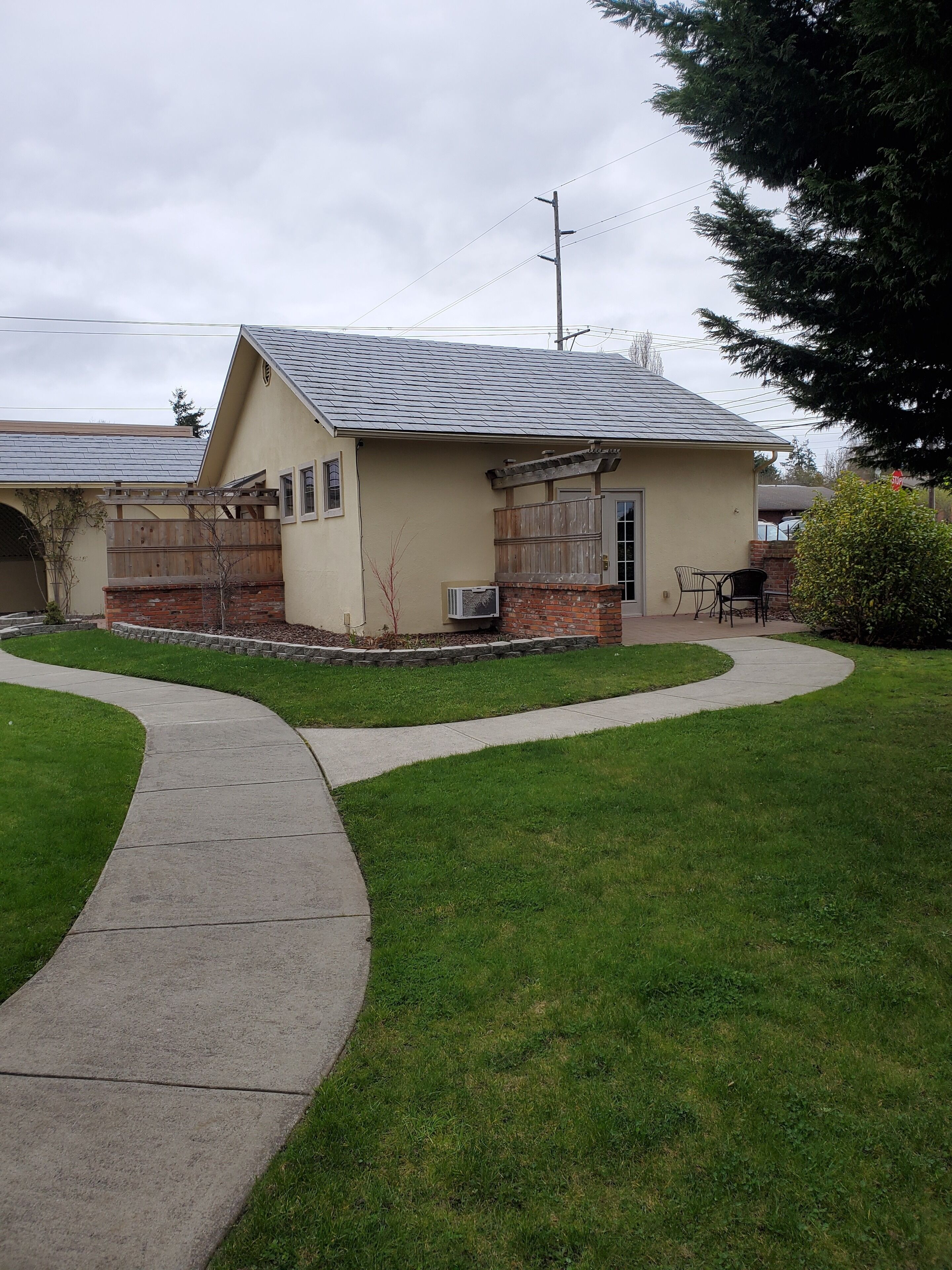 A single-story house with a sloped roof, a brick foundation, and a small front porch with a wooden railing.