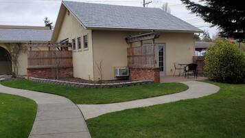 A single-story house with a sloped roof, a brick foundation, and a small front porch with a wooden railing.
