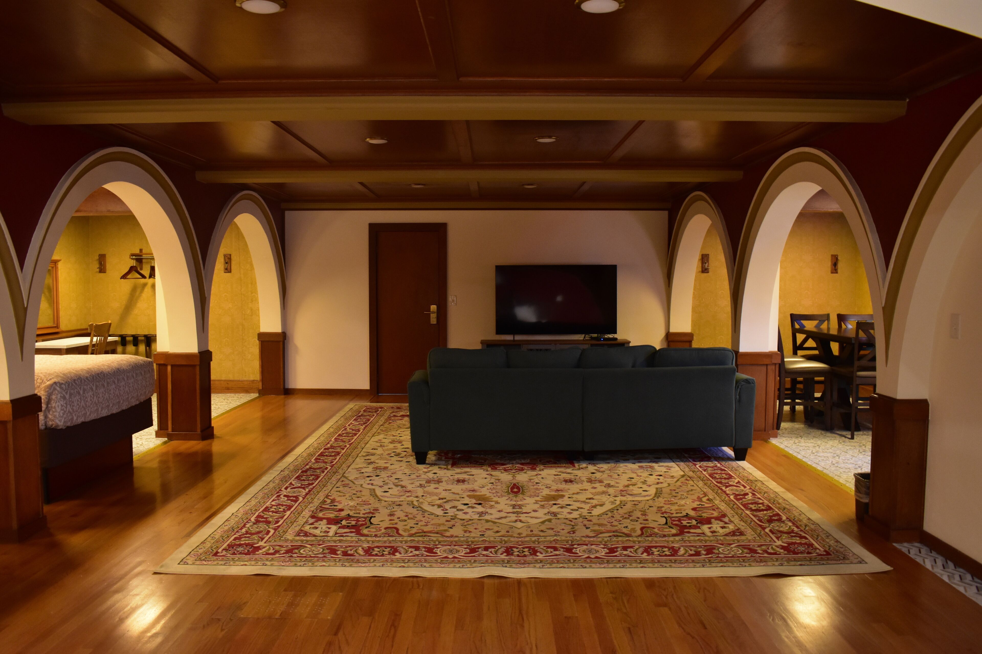 Uma sala de estar espaçosa com um sofá grande, piso de madeira e um tapete decorativo.