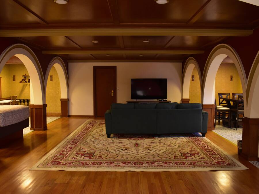 Uma sala de estar espaçosa com um sofá grande, piso de madeira e um tapete decorativo.