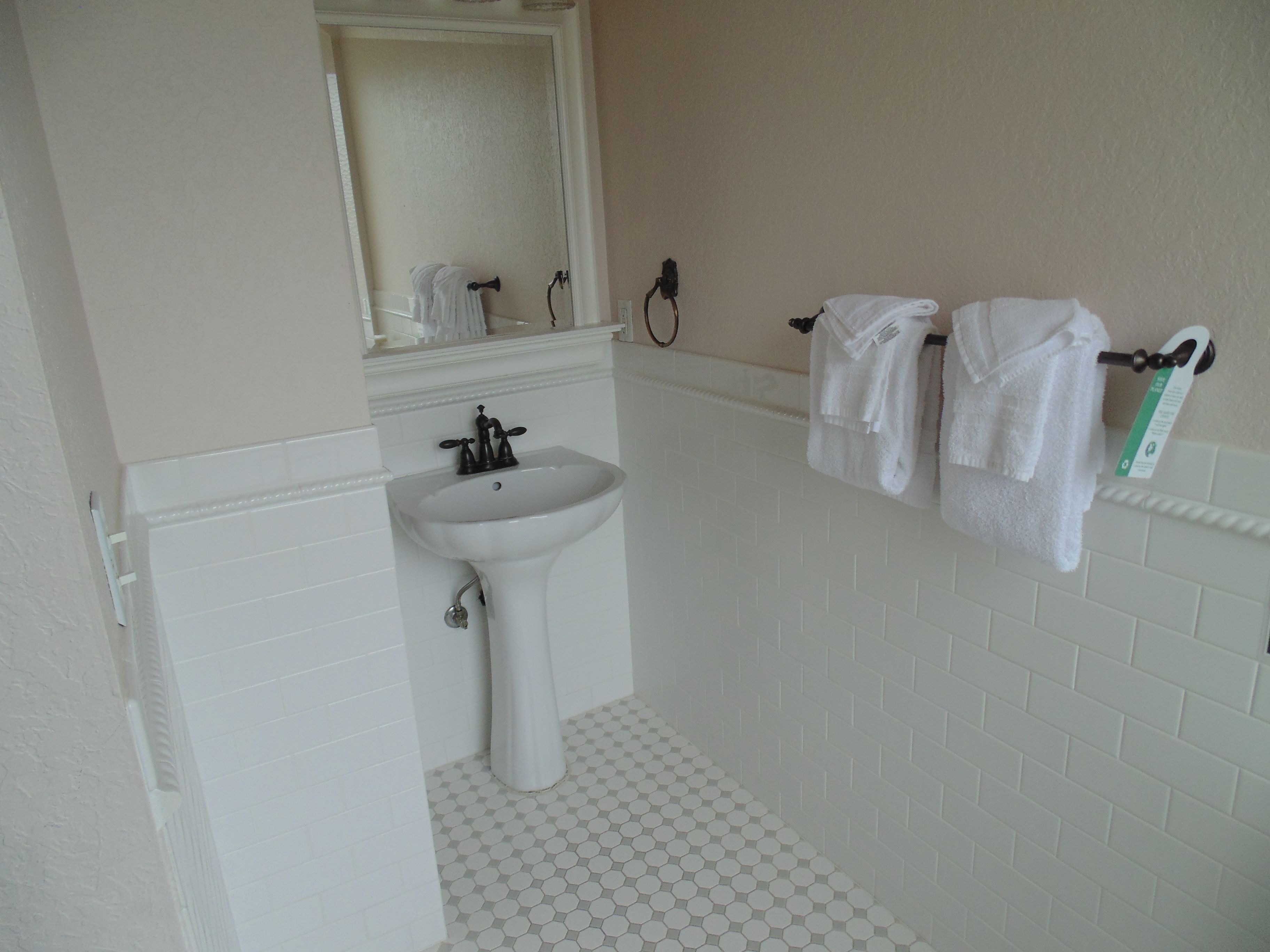 A bathroom with a white sink, a mirror above it, and a towel rack with two towels.