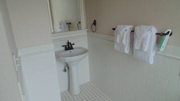 A bathroom with a white sink, a mirror above it, and a towel rack with two towels.