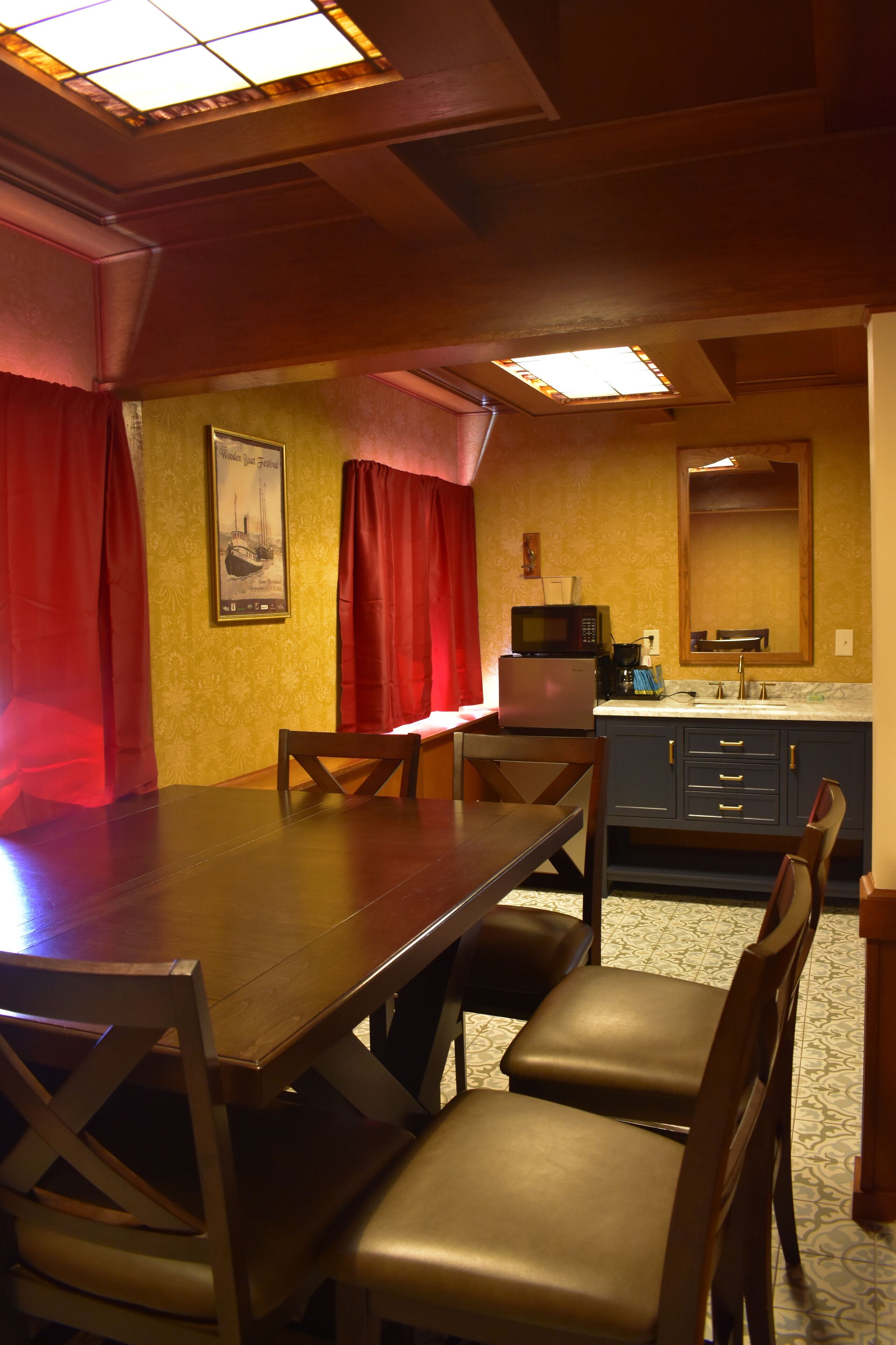 Comedor con una mesa y sillas de madera, un microondas y un lavabo al fondo.
