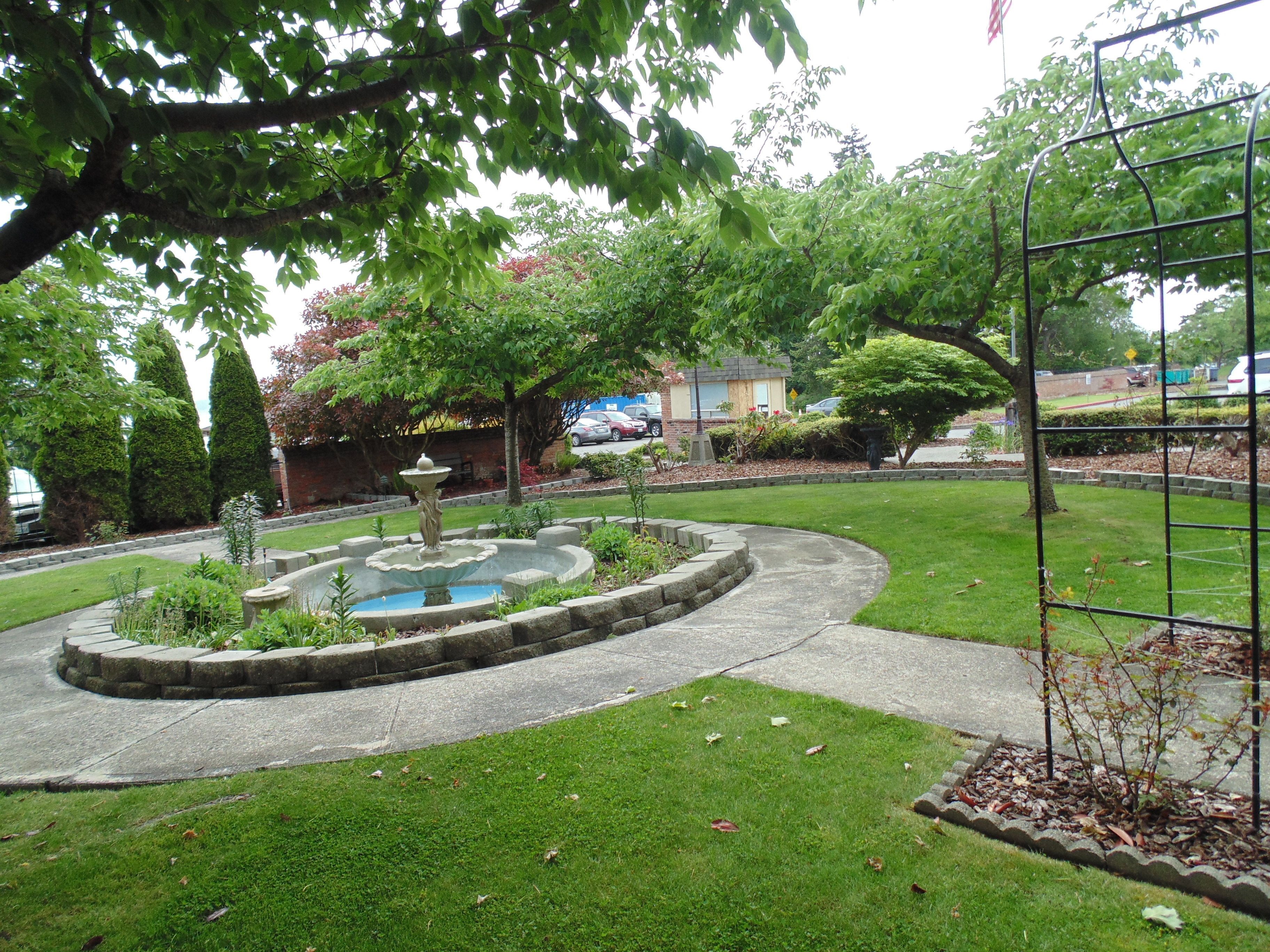 A landscaped garden with a central fountain, surrounded by a circular stone border.