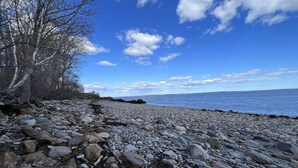 A rocky beach with a clear sky and calm sea. - High Tide Inn (Camden)