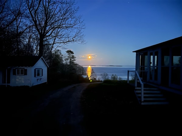 A coastal house with a view of the sunset over the water.