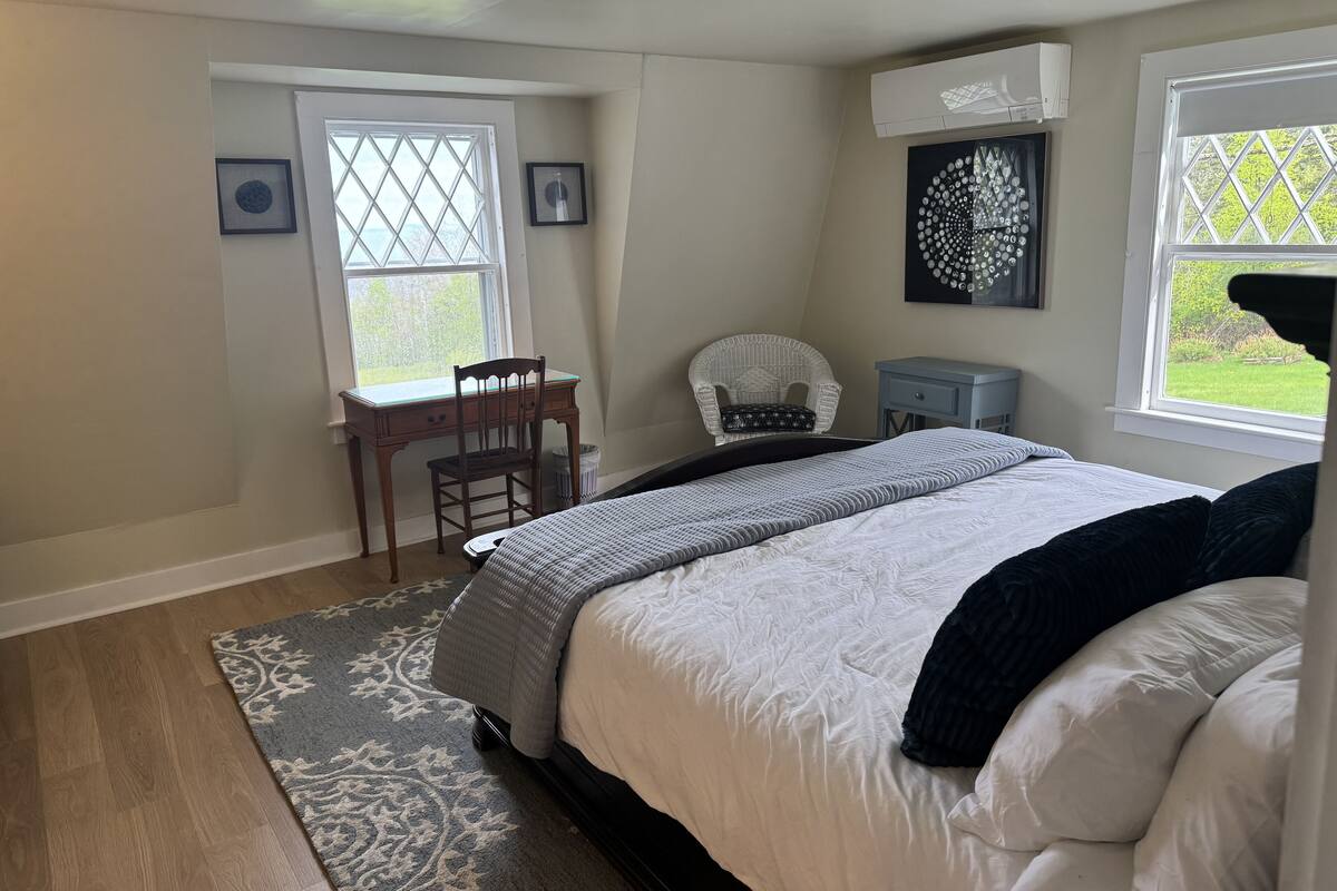 A bedroom with a bed, a desk, a chair, and a window.