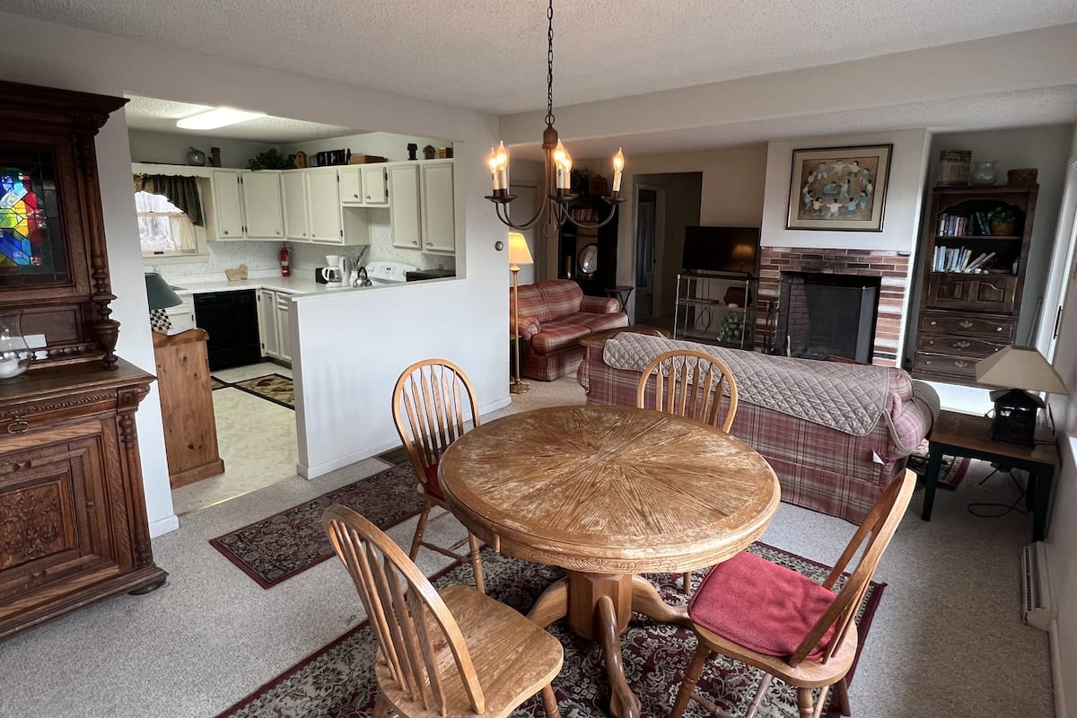 A cozy living room with a dining area, a kitchen, and a fireplace.