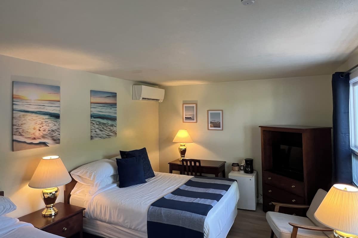 A hotel room with a bed, bedside tables, a desk, a chair, and wall-mounted artwork.