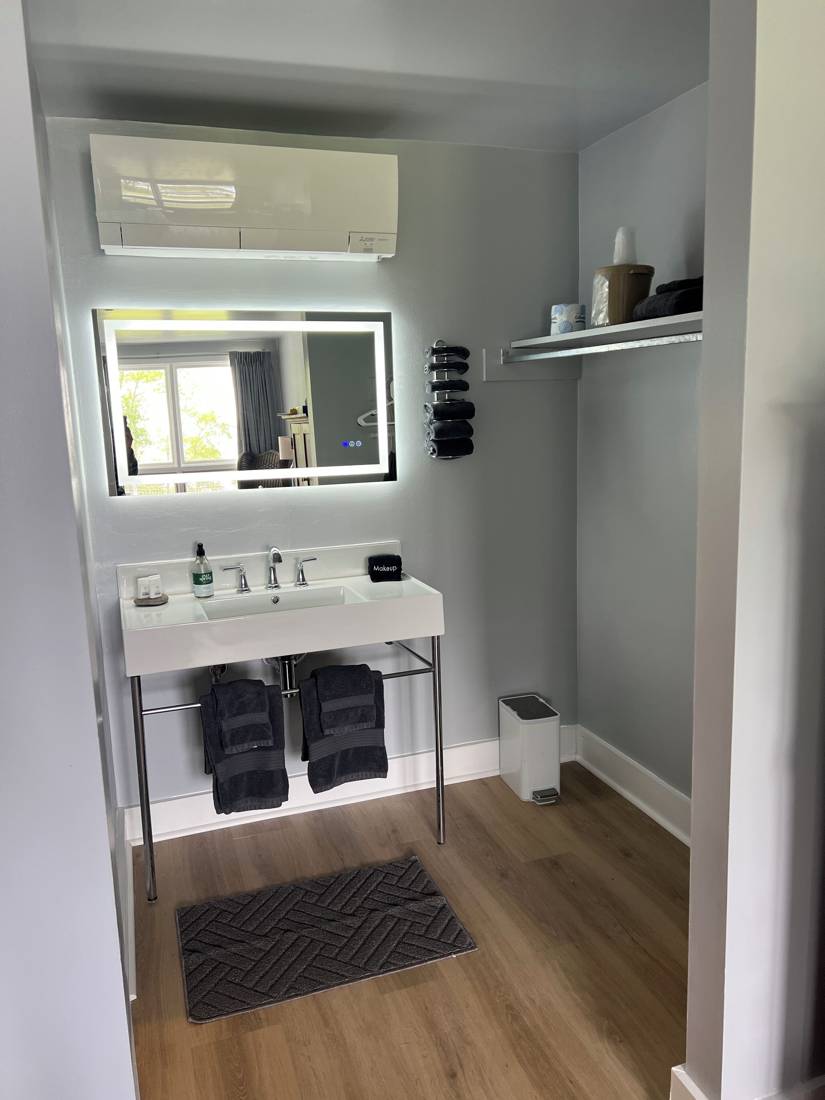 A modern bathroom with a large mirror, white sink, and towel rack.
