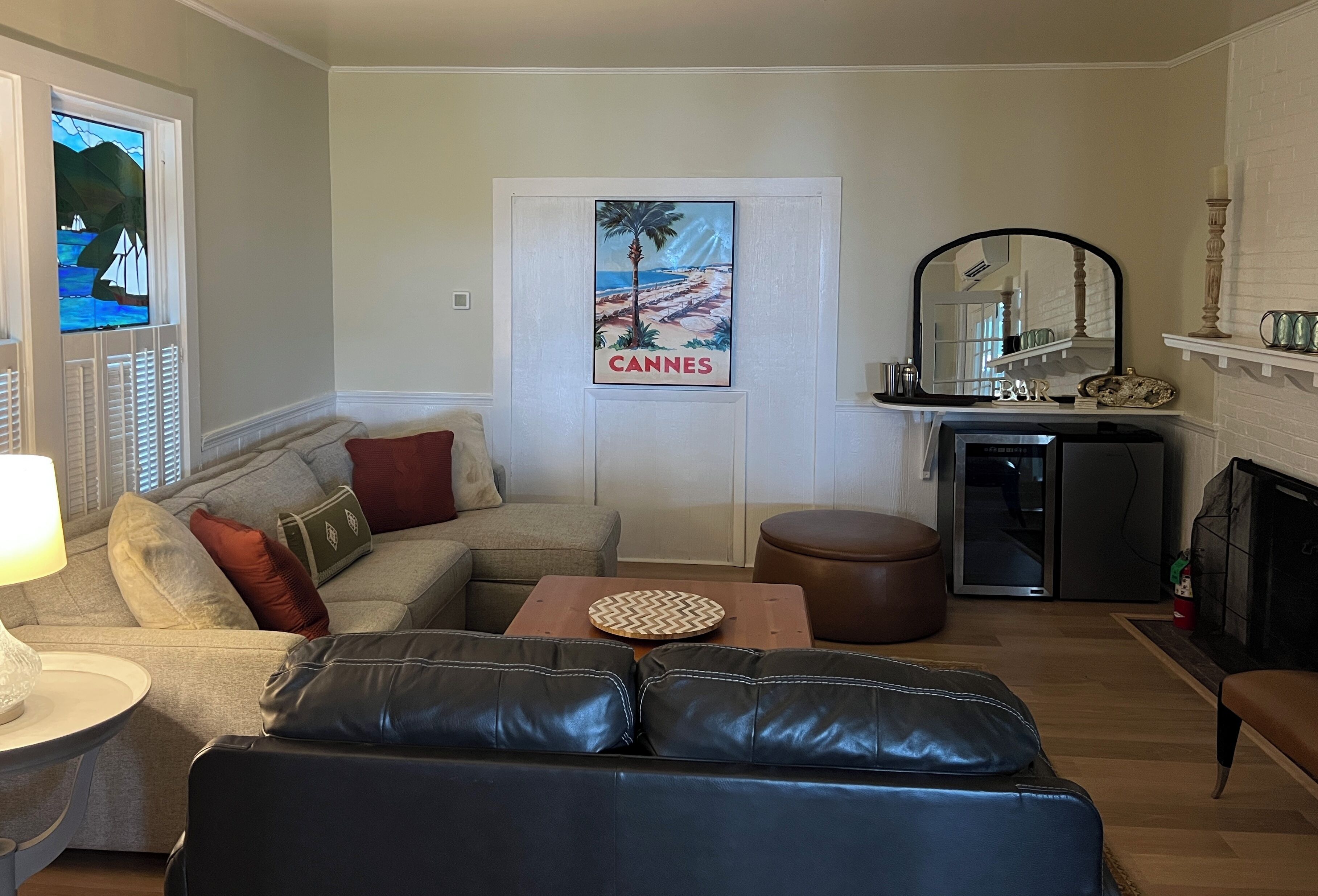 A living room with a sofa, a coffee table, a fireplace, and a poster on the wall.