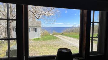 A room with a large window overlooking a grassy area and a body of water.