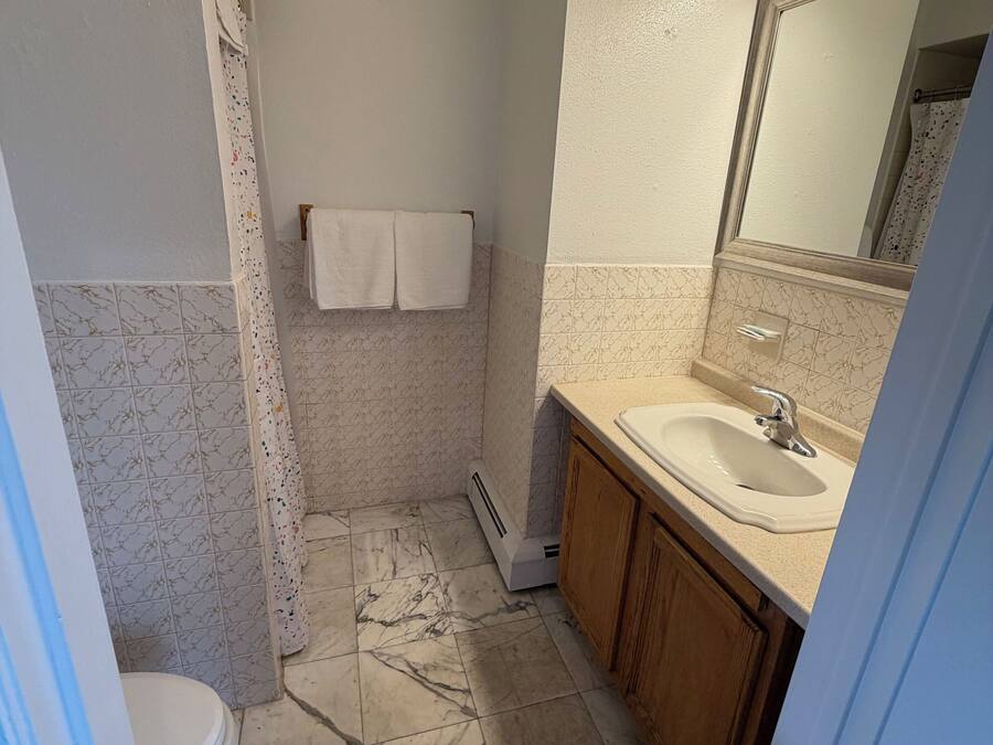 Een badkamer met toilet, wastafel, spiegel en douchegordijn.
