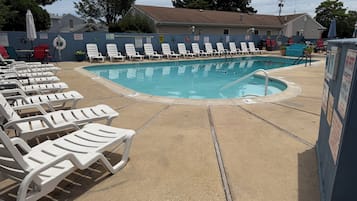 Una piscina al aire libre de temporada, sombrillas
