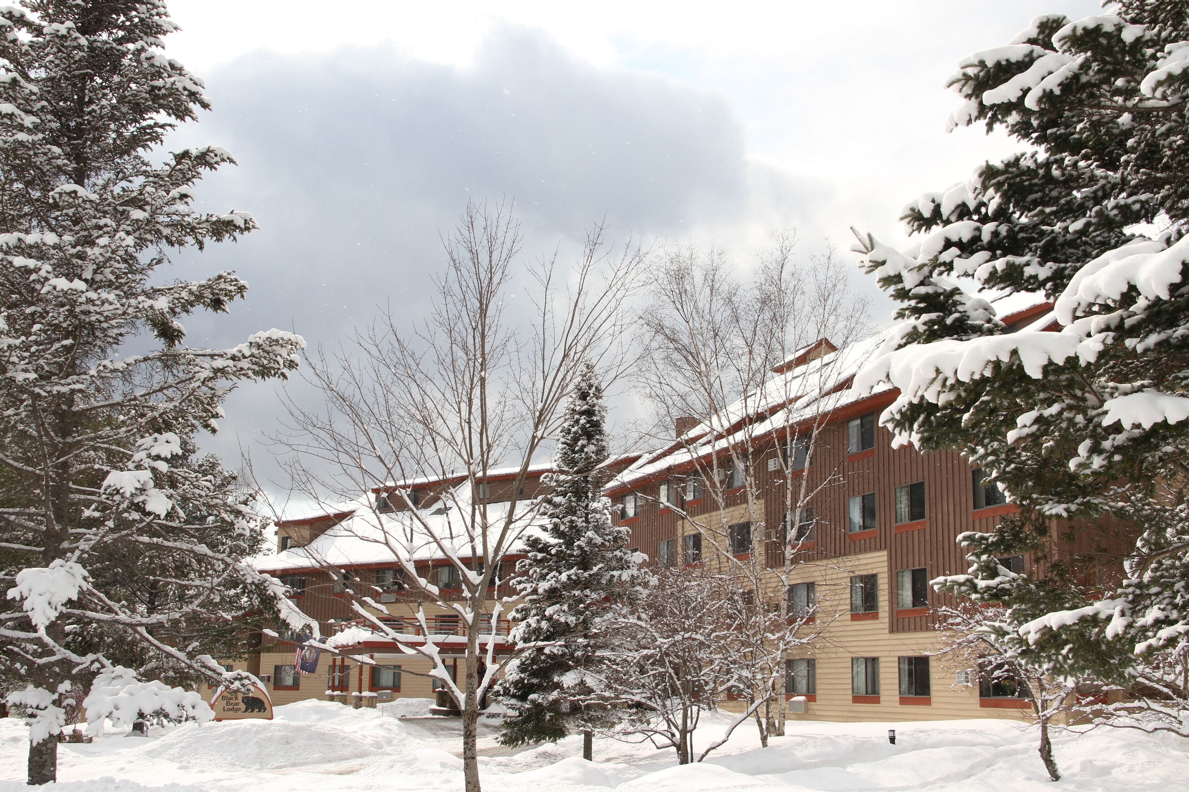 A snow-covered building with multiple windows and a red roof.