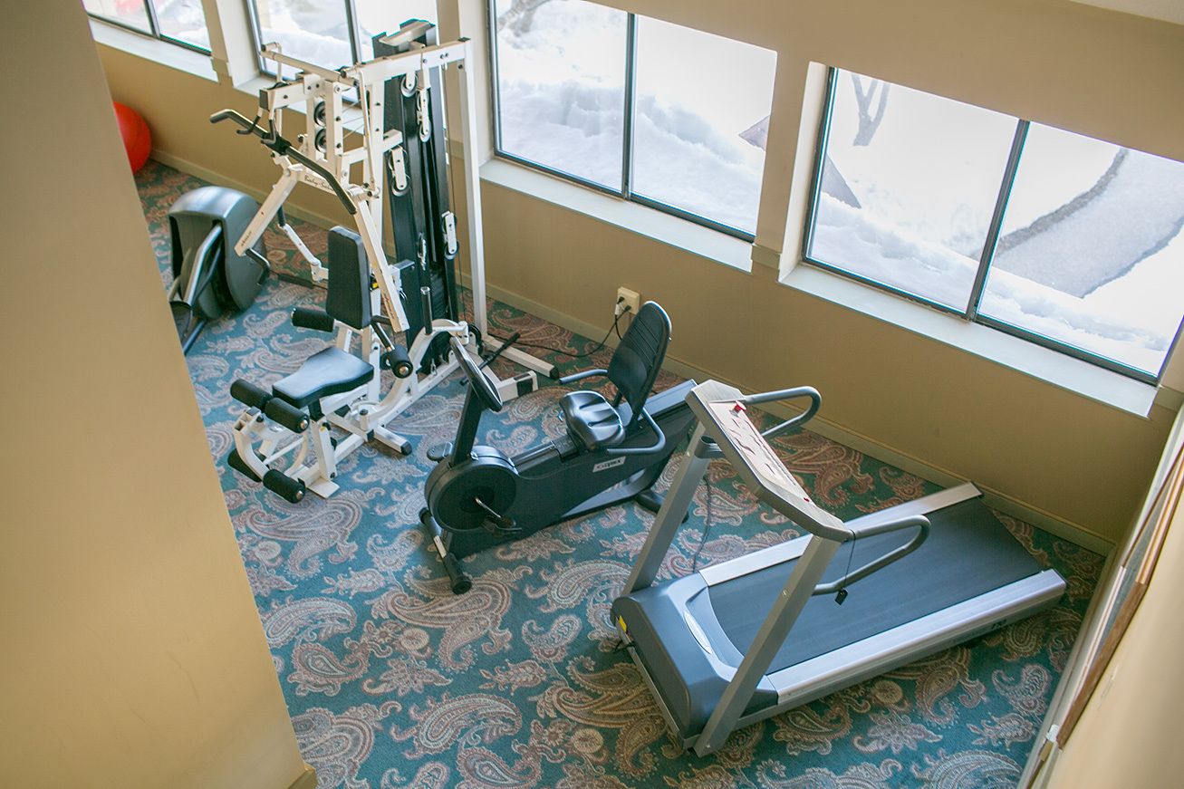 Une salle de sport équipée de matériel d’exercice, d’un tapis de course et d’un tapis à motifs.