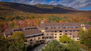 A multi-story hotel with a modern architectural design, featuring a central courtyard with outdoor seating and a small water feature. - Black Bear Lodge (Waterville Valley)